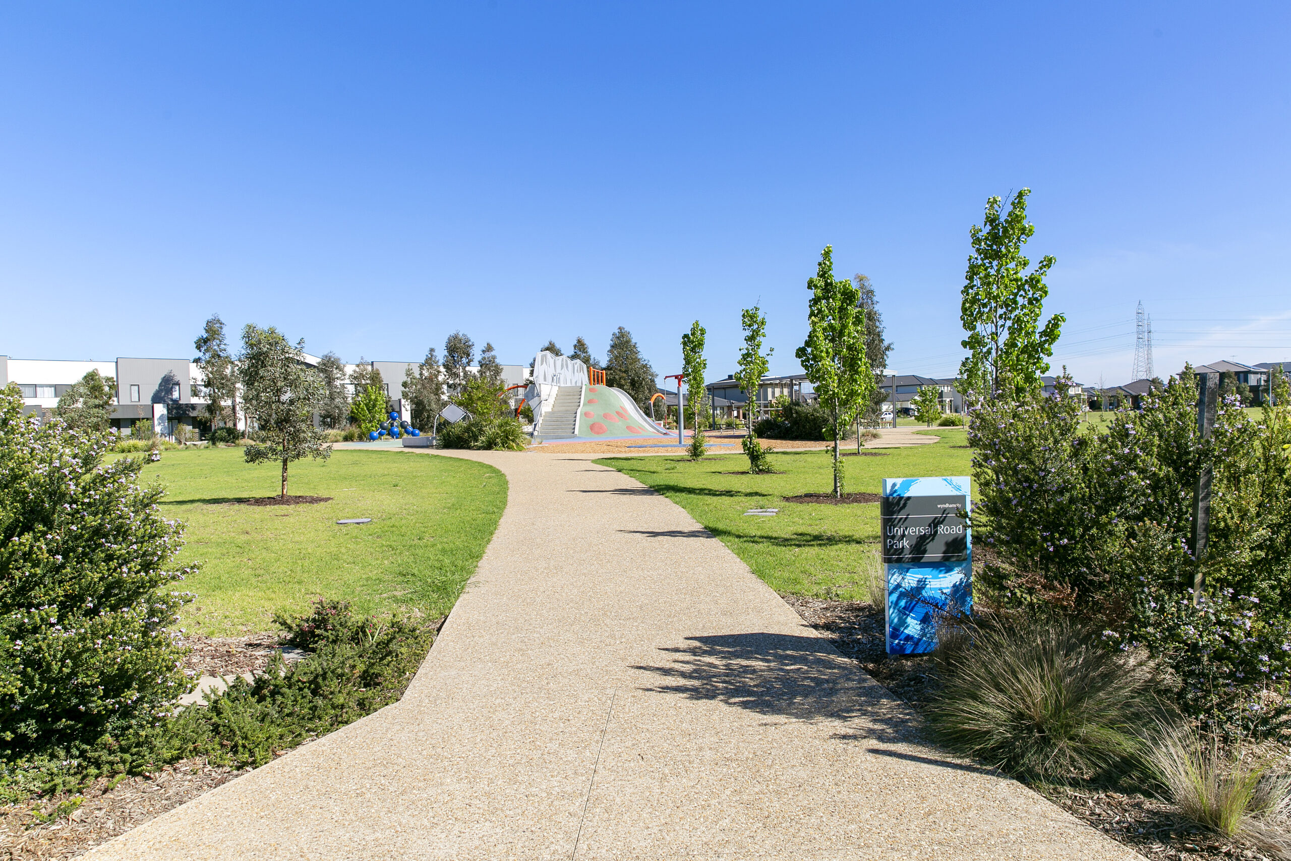 Landscaped walking pathway through a green community park with open lawns and trees in Tarneit