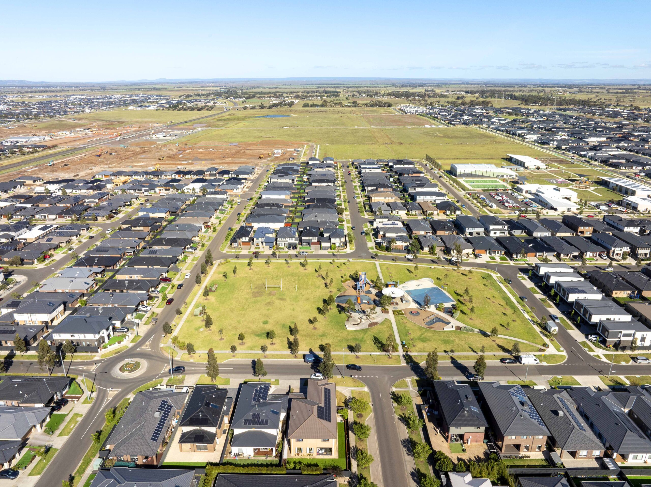 Aerial view of a residential community with landscaped parkland, walking paths and surrounding homes